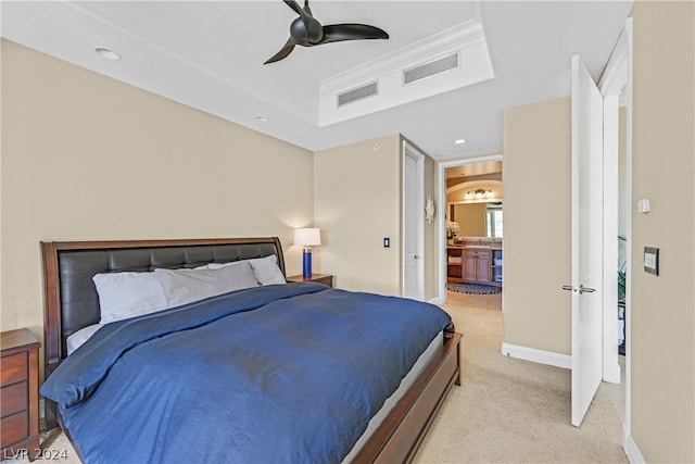 bedroom featuring ceiling fan, connected bathroom, a raised ceiling, light colored carpet, and crown molding