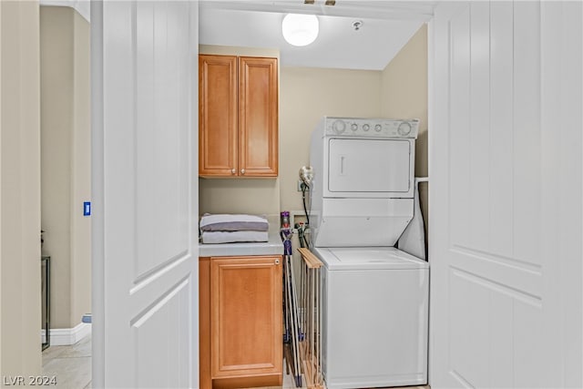 washroom featuring washer hookup, stacked washer / dryer, cabinets, and light tile floors