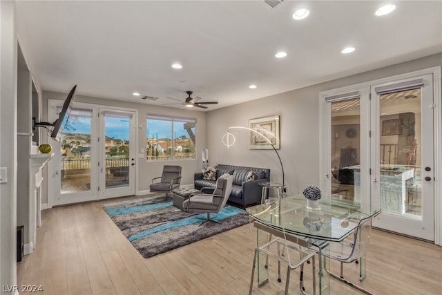 living room with a fireplace, light wood-type flooring, and ceiling fan