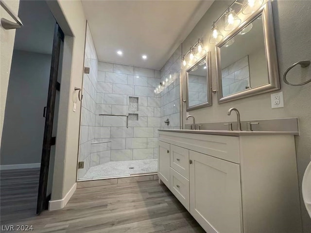 bathroom featuring oversized vanity, a tile shower, and hardwood / wood-style flooring