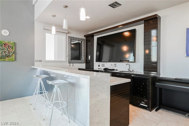 bar with sink, pendant lighting, light tile floors, and light stone counters