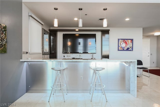 kitchen with light tile flooring, a kitchen bar, pendant lighting, and kitchen peninsula