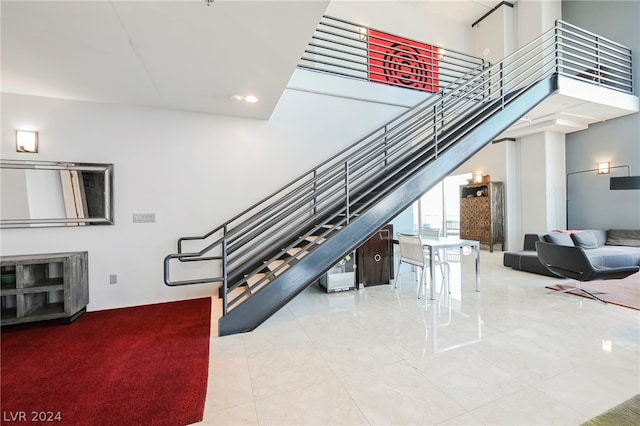 stairs featuring light tile floors and a towering ceiling