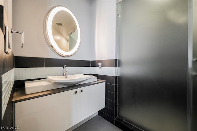 bathroom with tile floors, tile walls, vanity, and tasteful backsplash