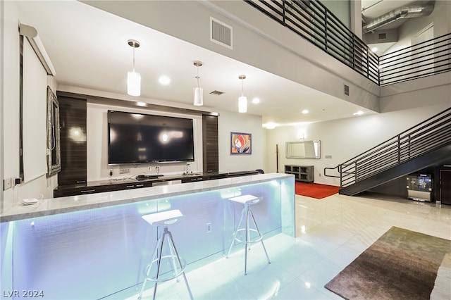 interior space with a towering ceiling, pendant lighting, light stone counters, and light tile floors