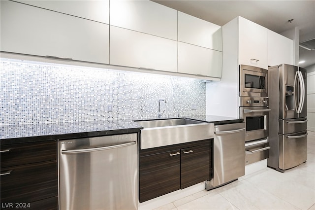 kitchen with appliances with stainless steel finishes, tasteful backsplash, light tile floors, dark brown cabinetry, and white cabinets