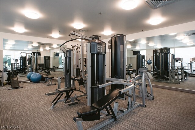 exercise room with plenty of natural light and dark colored carpet