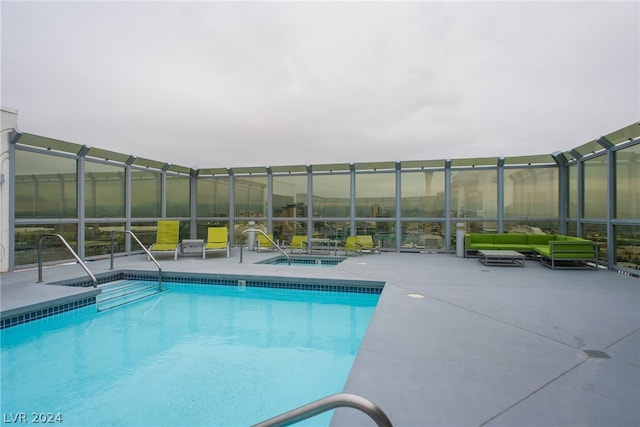 view of swimming pool with glass enclosure and a patio