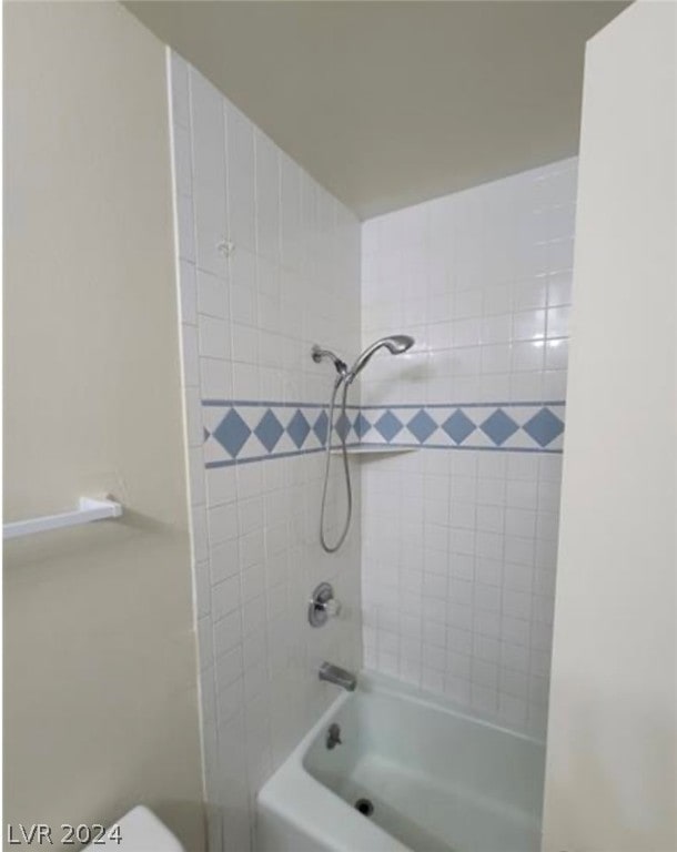 bathroom featuring tiled shower / bath combo and toilet