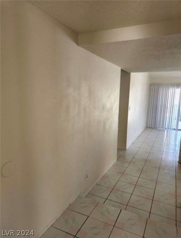 hall featuring a textured ceiling and light tile flooring