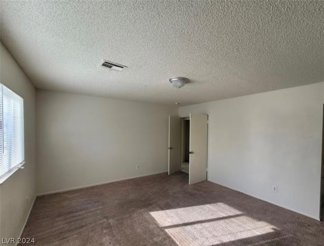 carpeted empty room with a textured ceiling