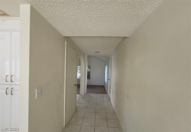 hall featuring a textured ceiling and light tile floors