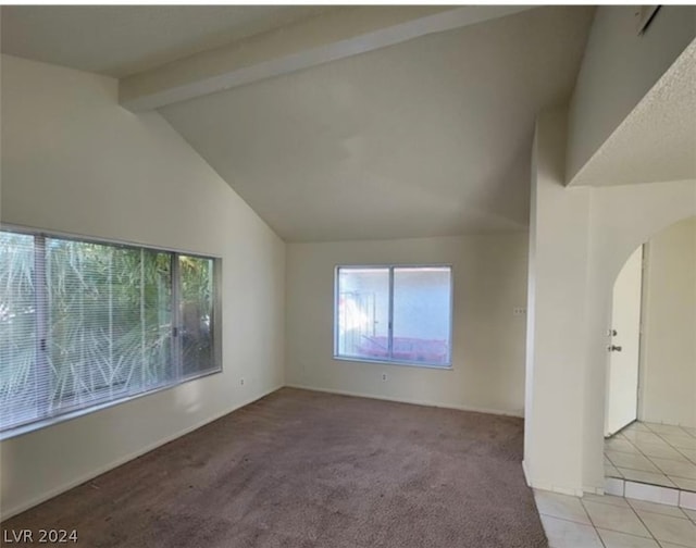 carpeted empty room featuring a healthy amount of sunlight and lofted ceiling with beams