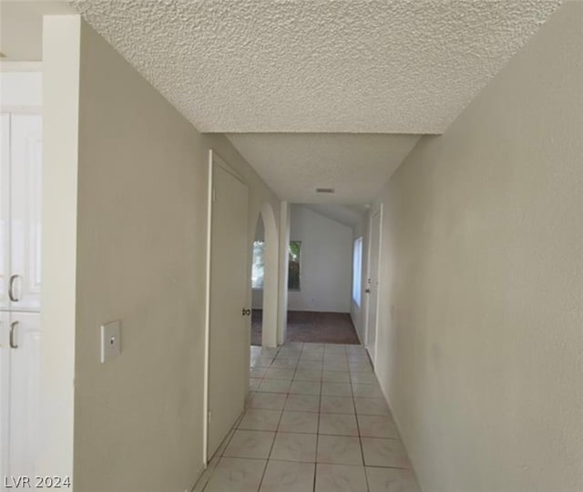 corridor featuring light tile flooring and a textured ceiling