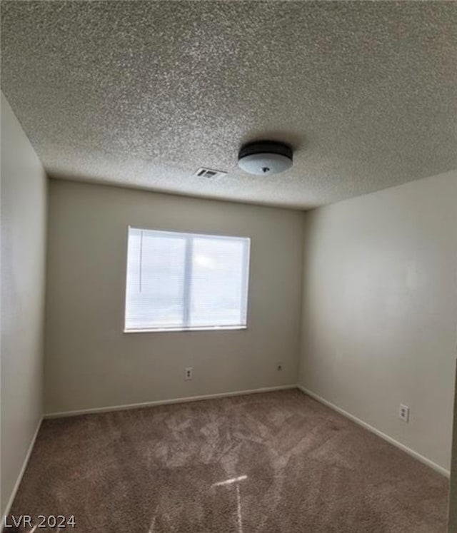 carpeted empty room with a textured ceiling