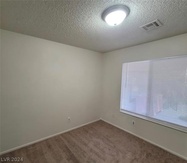 carpeted empty room with a textured ceiling