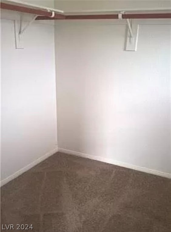 walk in closet featuring dark colored carpet