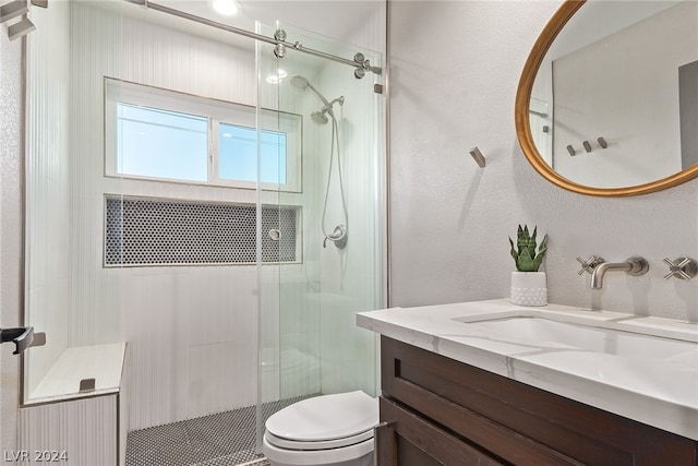 full bathroom featuring a textured wall, a stall shower, vanity, and toilet