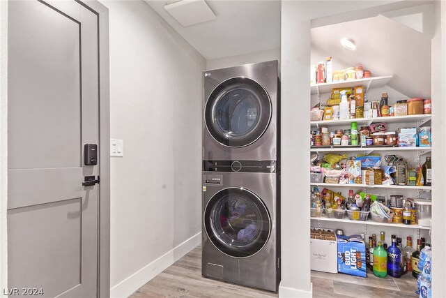 washroom with light wood-type flooring, laundry area, baseboards, and stacked washing maching and dryer