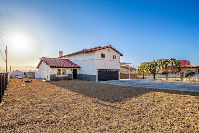 mediterranean / spanish house with a tile roof, stucco siding, concrete driveway, fence, and a garage