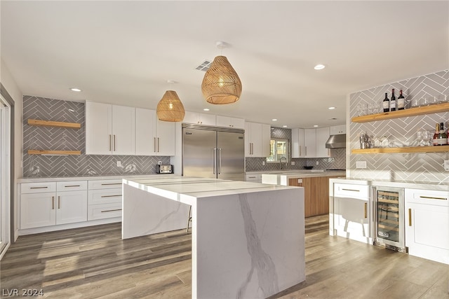 kitchen with wine cooler, a kitchen island, white cabinets, open shelves, and stainless steel built in refrigerator