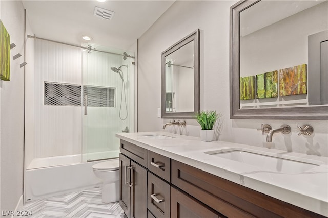 full bathroom featuring double vanity, a sink, toilet, and bath / shower combo with glass door