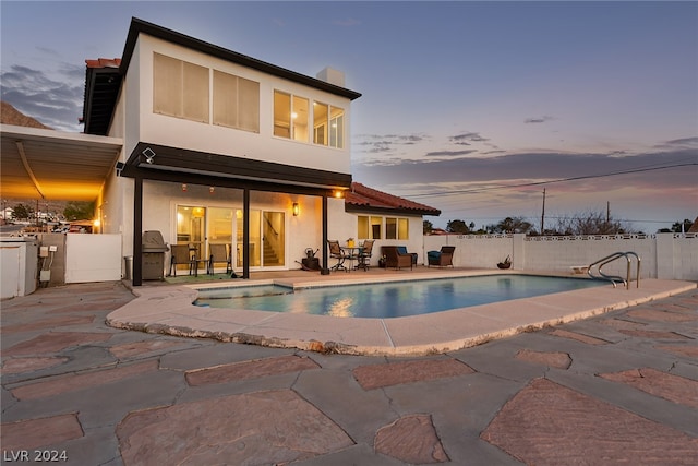 back of house featuring a fenced in pool, a fenced backyard, a patio, and stucco siding