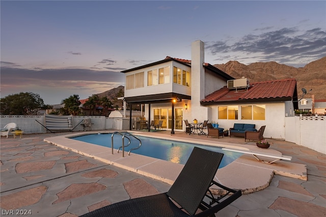 back of house at dusk with a patio, a fenced backyard, a mountain view, and stucco siding