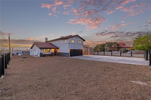 view of front of home featuring a garage, stone siding, fence, and stucco siding