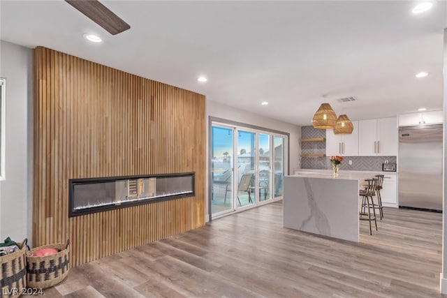 kitchen featuring pendant lighting, open shelves, white cabinetry, stainless steel built in fridge, and a kitchen breakfast bar