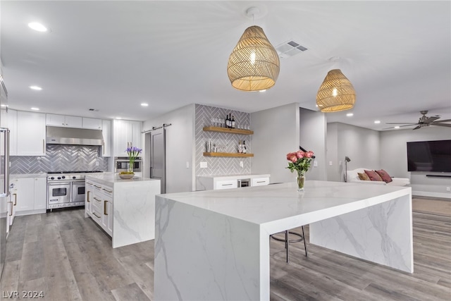 kitchen with a barn door, a kitchen island, white cabinetry, and pendant lighting