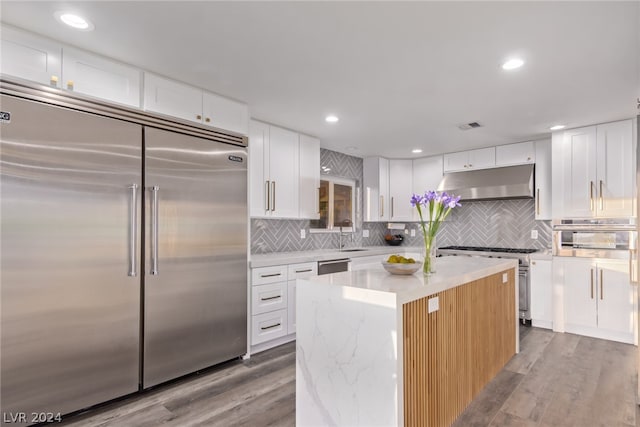 kitchen featuring premium appliances, a center island, white cabinets, and under cabinet range hood