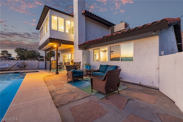 back of house at dusk featuring a fenced backyard, a patio, an outdoor hangout area, and stucco siding