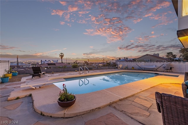 pool at dusk featuring a fenced backyard, a fenced in pool, and a patio