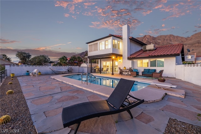 view of swimming pool with a patio area, a fenced backyard, a mountain view, and a diving board