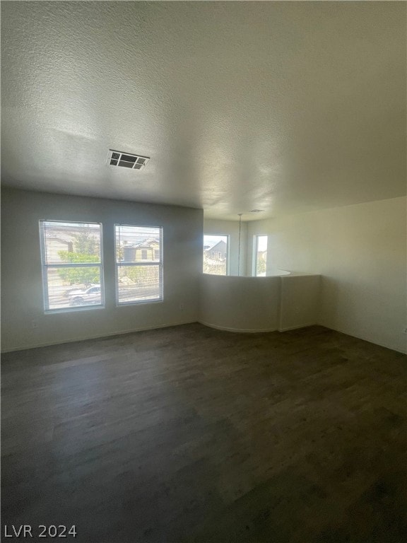 empty room with a textured ceiling and hardwood / wood-style flooring