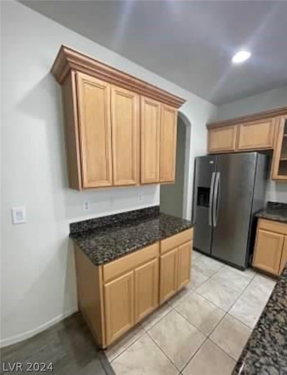 kitchen with stainless steel fridge, dark stone countertops, and light tile patterned floors