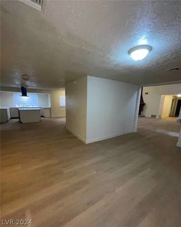 basement featuring a textured ceiling and light hardwood / wood-style floors