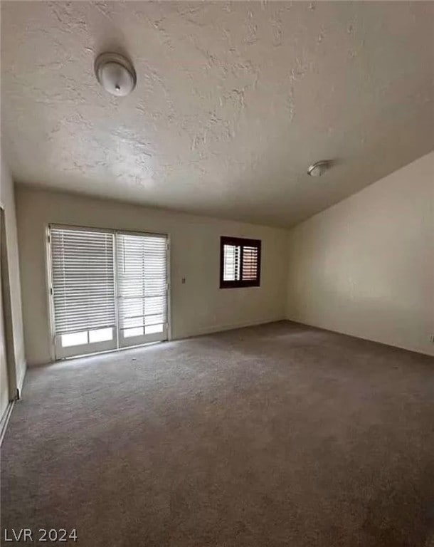 carpeted empty room featuring a textured ceiling