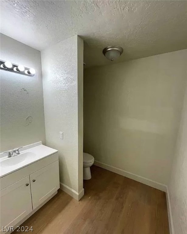 bathroom with vanity, a textured ceiling, wood-type flooring, and toilet