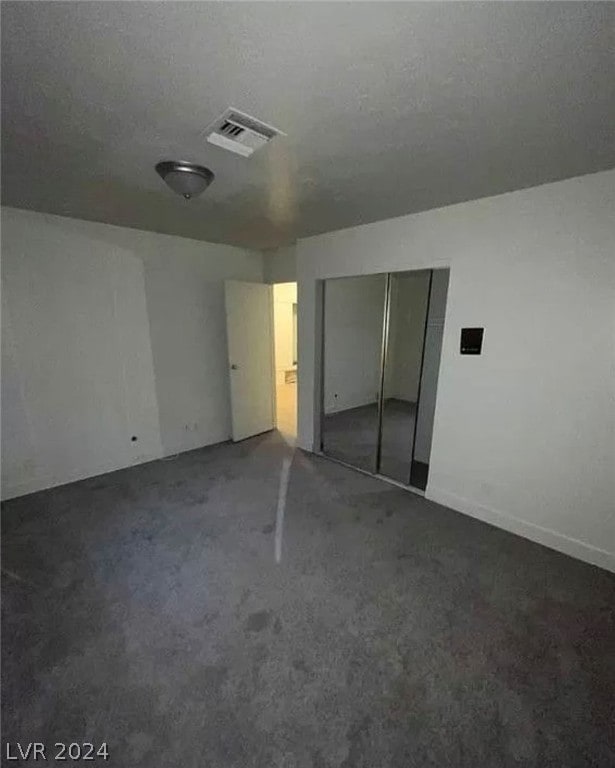 unfurnished bedroom with a closet and dark colored carpet