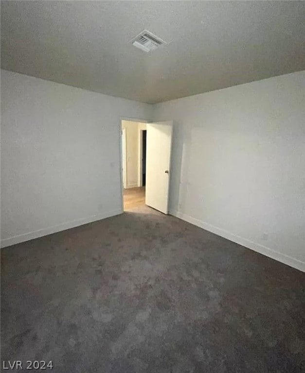 unfurnished room with a textured ceiling and dark carpet