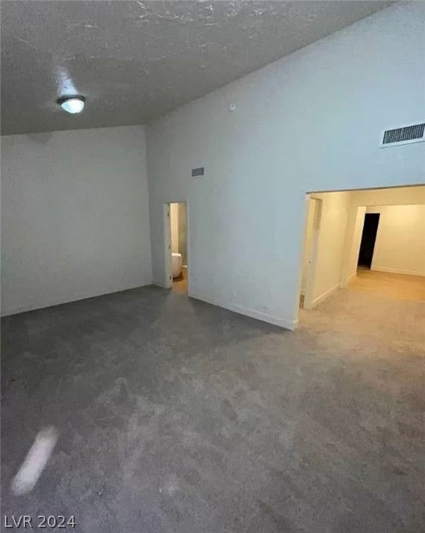 spare room with a textured ceiling and dark colored carpet