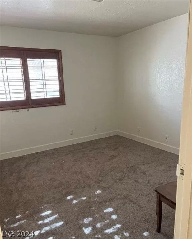 empty room with a textured ceiling and dark carpet