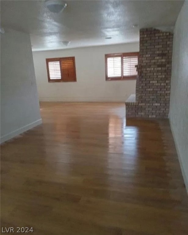 empty room with brick wall and dark hardwood / wood-style floors