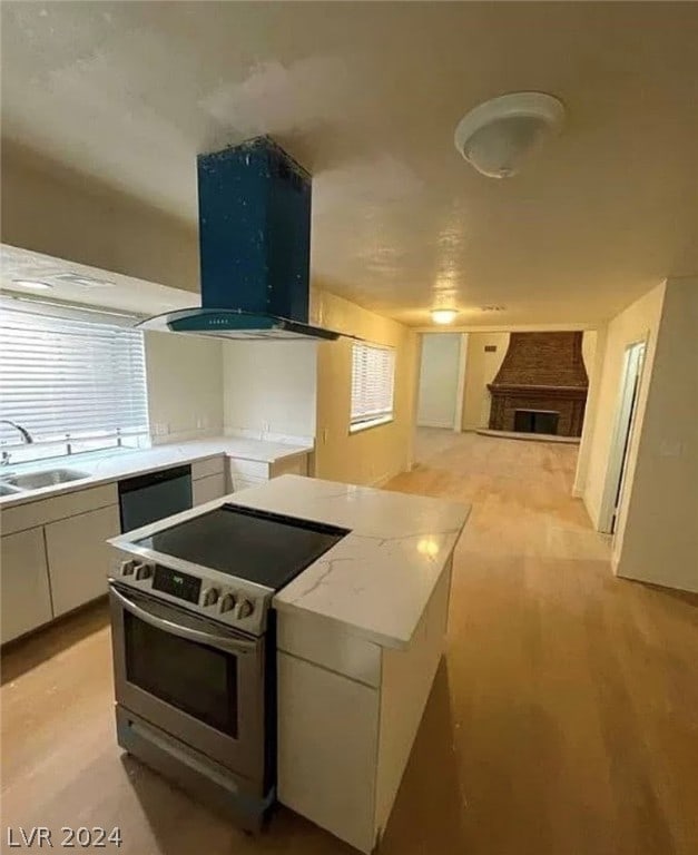 kitchen with exhaust hood, stainless steel appliances, light stone countertops, white cabinets, and sink