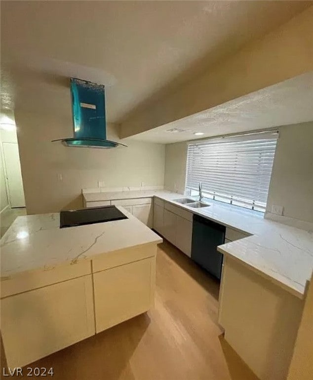 kitchen featuring light wood-type flooring, wall chimney range hood, light stone counters, sink, and black appliances