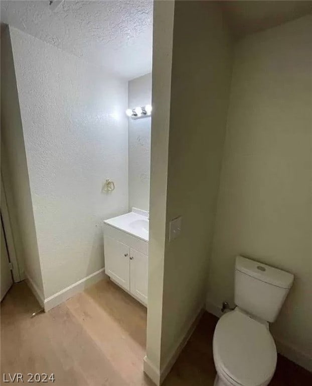 bathroom featuring a textured ceiling, toilet, vanity, and hardwood / wood-style floors