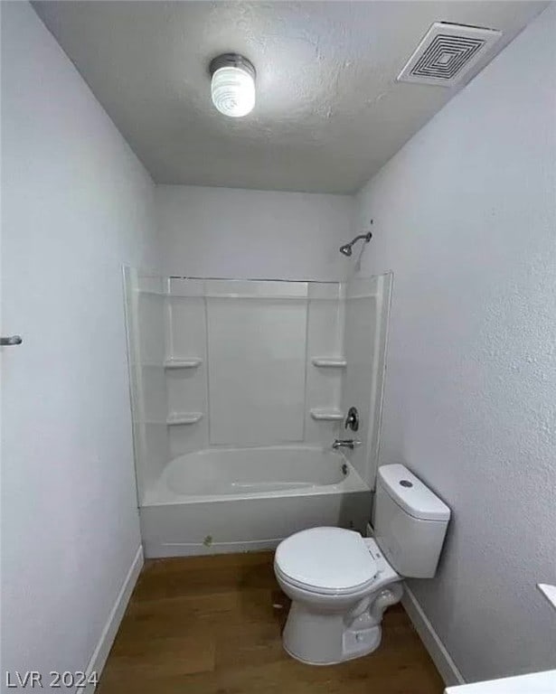 bathroom with toilet, wood-type flooring, and washtub / shower combination