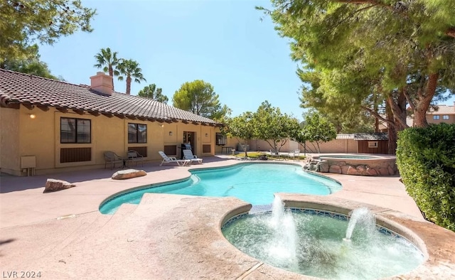 view of pool with an in ground hot tub, pool water feature, and a patio area